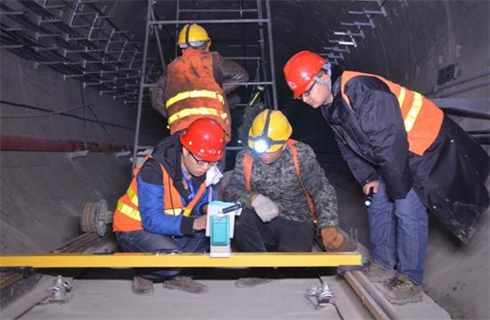 随着我国公路建设规模的日益扩大，公路隧道建设取得了很大的发展,公路隧道具有断面大，地质条件和施工技术复杂等特点，加之设计时对地质条件的认识不够全面准确，通车后存在的隧道老化、运营管理和维护等方面的原因，致使我国公路隧道的病害问题十分严重，隧道衬砌背后的空洞问题就是其一，由此引起的拱顶上鼓及衬砌内缘压裂、掉块的现象严重影响到公路隧道的使用寿命。因此加强对隧道衬砌背后空洞的检测判断和处理，是隧道工程病害处理的重要一环。 一、检查目的和必要性 目的：隧道拱部衬砌出现空洞剥落掉块直接危及行车安全，但衬砌内部病害隐蔽，无法通过肉眼发现，通过人工敲击可有效发现衬砌内部空洞等隐患，并对无损检测资料有针对性的进行验证。 必要性：通过隧道找部衬砌人工敲击检查。可对大部分拱部病害及早发现并进行整治，从而降低运营期间拱部衬砌剥落掉块的风险。 二、检查时机和范围 1、检查时机 隧道二次衬砌贯通后，接触网安装前为最佳检查时机，接触网安装后通电前次之，通电后则须停电 。 2、接触网安装前、后敲击检查的区别 接触网安装前后，敲击方法、车辆、工具基本相同。主要区别： （1）接触网作业车检查平台，升起高度或检查架搭设高度不同，接触网安装前接触网作业车检查平台升起高度或检查架搭设高度距拱顶3米左右，拱顶至拱腰均易于敲击，接触网安装后接触网作业车检查平台升起高度，或检查架搭设高度距离拱顶至少4米。 （2）检查槌长度不同。接触网安装前检查槌长度为2米左右，接触网安装后检查槌长度为2.5米至4.6米。 3、检查范围 当使用供电检查车或轨道车平板上搭检查架检查时，从拱顶中心线至起拱线半幅为一次敲击检查范围，当使用检查架检查时，从线路左侧起拱线至线路右侧起拱线全幅为一次敲击检查范围。 图片描述(最多50字) 三、检查前准备工作 1、车辆：接触网检查车，平板车搭检查架，在钢轨或侧沟盖板上推进检查架，以双线隧道，轨顶至拱顶9米为例，且检查平台距接触网立柱等侵限物体保持10至20厘米间距。 （1）采用接触网检查车检查无接触网时，检查平台高度以距拱顶3米为宜，检查平台横向放置，有接触网时，检查平台高度以距拱顶5米为宜，检查平台纵向放置，需要时再旋转到横向位置。 （2）平板车搭检查架，钢轨上安装检查架或侧向水沟盖板和两线间底板顶搭设检查架，无接触网时，检查平台高度以距拱顶距离3米为宜，检查平台横向宽度可达9米，有接触网时，检查平台高度距离拱顶4米为宜，两线间平台需下凹0.5米，检查平台横向宽度可达9.5米。 图片描述(最多50字) 2、工具：大型工具有：接触网检查车、轨道车（含平板车）、检查架（根据净空定制）；小型工具有：手提式强光手电筒、头部矿灯、检查槌（空心钢管直径30mm，一端焊接一根尖头钢筋一端焊接一根平头钢筋，长度2至4.6米不等），卷尺、塞尺、钢直尺、喷漆、桶装油漆、漆杆（4.5米长竹竿一端绑扎油漆刷）、检查梯、对讲机、照相机、手套、安全带、安全帽、防护衣、护目镜、口罩、记录本、黑水笔等。 3、人员：作业小组由8人组成（使用接触网检查车或轨道车时需1人持对讲机指挥车辆），检查车分工为：3人持检查槌（敲击半幅拱顶线路正上方拱腰，线路侧方拱腰至起拱线），2人听敲击音并标记，1人记录并拍照，1人指挥并负责安全检查和提示，检查架分工为：4人持检查槌敲击拱顶、拱腰，2人听敲击音标记并负责指挥及安全检查提示，2人记录并拍照。 四、敲击检查程序 1、开窗安排：提前一天申请检查天窗，天窗时间本线封锁不少于8小时，邻线限速每小时20公里，根据批准的天窗计划，驻站联络员在《行车设备登记簿》内登记，列车高度员下达调度命令；施工负责人接到调度命令后按调度命令凭证发车；检查车到指定地点后，立即设置防护体系。在距离检查地点20米处现场防护员设置移动停车信号弹（灯），在距离施工地点800米两端防护员设置显示停车手信号；邻线防护需设置移动减速信号牌和减速地点标。天窗作业计划结束前机车返回申请停靠点。驻站联络员与现场防护员在执行防护任务时，应佩戴标志携带通信设备，现场防护员还应携带必要的防护用品；随时掌握现场和列车运行情况。发现异常情况及时通知车站值班员和施工负责人。驻站联络员应与现场防护员时刻保持联系。 图片描述(最多50字) 2、敲击作业：车辆行驶速度控制在每小时5公里以内，检查架推进速度控制在每小时1公里以内，行进过程中进行敲击，凭敲击声音辨别是否存在空洞，声音异常时停车仔细敲击确认空洞范围，施工缝、混凝土修补、蜂窝、混凝土表面有杂物（如钢筋头、注浆管等）、施工冷缝、止水带外露、防水板外露、闭环裂纹、变形外鼓等重点处所均停车进行仔细敲击检查。 3、照明配置、照度、范围：BAD305手提式防爆探照灯2台，BAD212微型手持防爆调光工作灯2台，LED722B充电头灯2台，照度不低于250勒克斯，照明可视距度10m。 4、敲击人员自我防护注意事项：（1）作业前将劳动防护用品穿戴整齐‘（2）攀爬脚手架时，要站稳扶牢。登上检查平台后，须首先挂好安全带和安装栏杆扶手，工具应放置稳固。（3）接触网检查车检查平台、检查架移动前应通知作业人员停止作业，将工具摆放稳固，人员蹲下扶牢，目视前进方向，机车指挥人员发现侵限物体要及时停车，拆除侵限物体。检查架移动就位后，必须设好滚轮制动和斜撑后，方可作业。（4）检查小组人员必须团结协作、听从指挥，相互提醒安全注意事项，做到自控、互控。（5）人员站位要相对固定，避免检查槌等工具碰伤人员。（6）清除衬砌掉块时，应高声提醒所有人员注意安全，下方无人时，方可进行作业。（7）邻线来车时，须停止作业，小稳扶牢，检查工具不得侵限。 5、检查架的组成：同槽钢跑道、脚手架滚轮及抽动装置、 钢管立柱、钢管横撑、钢管斜撑、十字卡、万向卡、脚手板及铁丝、栏杆及锁口钢筋、反光标等组成。 6、缺陷确认：敲击声音清脆，发出“铛、铛、铛”的声音说明衬砌混凝土比较密实，如果敲击声音沉闷出现“咚、咚、咚”的声音，说明衬砌混凝土存在空洞，附带检查内容包括衬砌掉块、裂纹、渗漏水、露筋、钢筋保护层厚度不足、蜂窝麻面、混凝土夹带杂物等。 7、问题标记：发现问题停车采用红油漆标记问题范围，测量（估算）相关尺寸，将病害类型、尺寸等数据详细记录、拍照存档，如在空洞外边界标记面积范围，在裂缝起终点位置用箭头（箭头朝向裂纹处）标记长度，箭头旁标出裂纹宽度值，同时将问题类型、编号、里程用红油漆在问题位置边墙上进行标记，以便日后整改。标记形式“BLWKD-1-K493+179”，BLW指白力坞隧道，KD指拱部空洞，1指编号为1号，K493+179指空洞里程，若一个隧道有多处空洞，序号按里程从小到大排序，依次为1、2、3、4.......。 8、资料整理：为避免出现场检查发现问题记忆模糊、相似问题相互混淆的情况，检查小组每天须将当天检查发现的问题，根据病害类型、部位、按静态验收报告格式进行梳理、统计，将照片编辑相应文字说明。